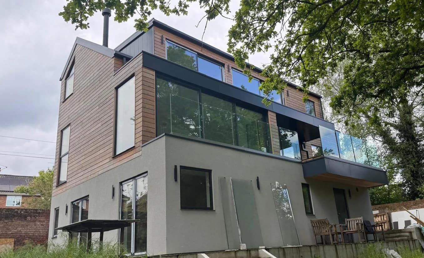 Rear view of a timber clad home with balcony glazing