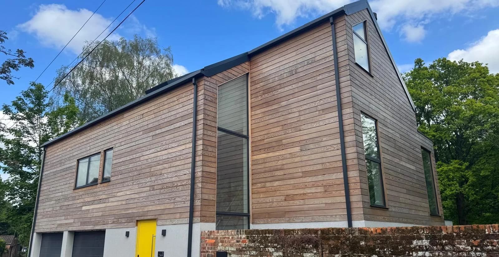 Side view of a timber clad home with garage doors